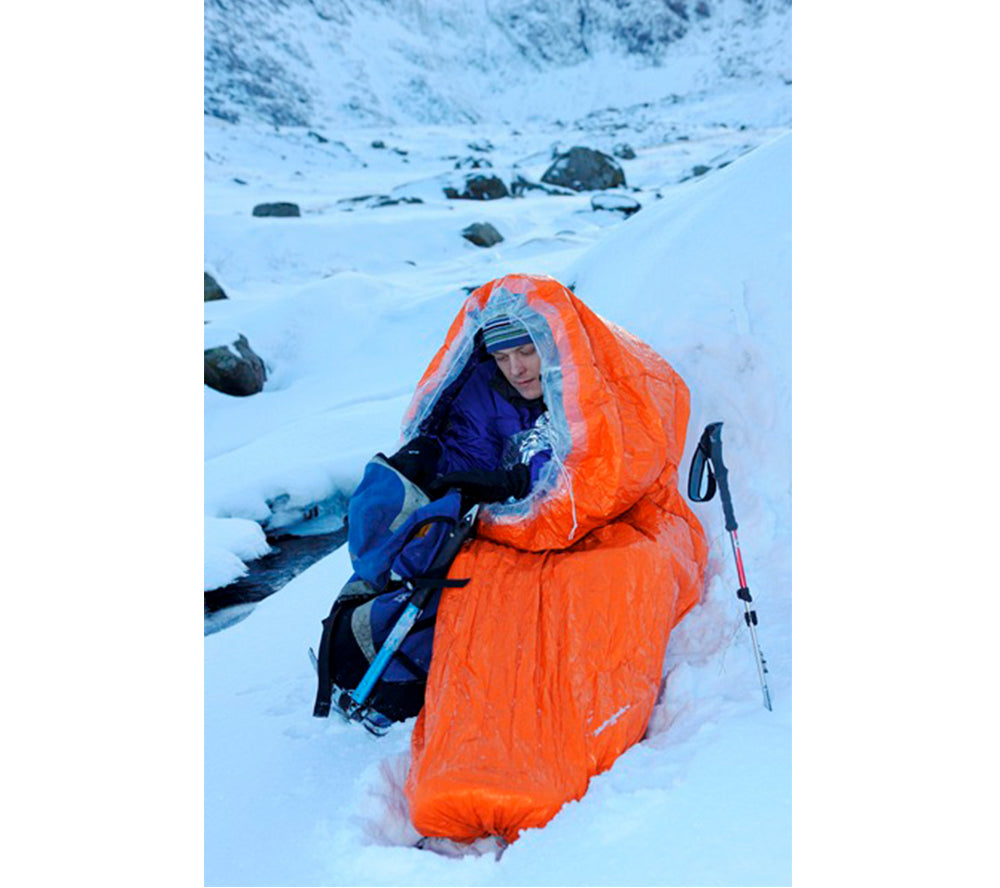 An orange Blizzard Survival Bag in use in extreme cold weather.